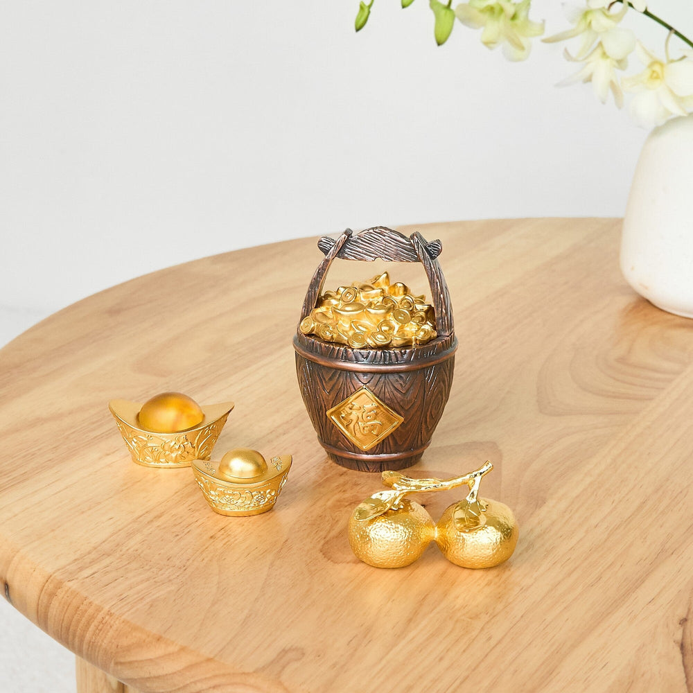Risis Abundance Money Barrel - A wooden-textured basket filled with gold ingots sits beside golden Chinese ingot-shaped decorations on a polished wood surface, conveying a sense of prosperity and cultural artistry.