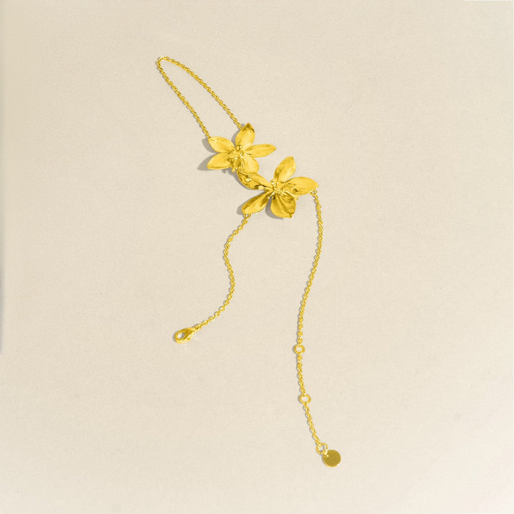 Risis Aeridovanda Blooms Hand Chain - A golden necklace with a three-dimensional, five-petaled floral charm and delicate chain details, exuding elegance and simplicity.