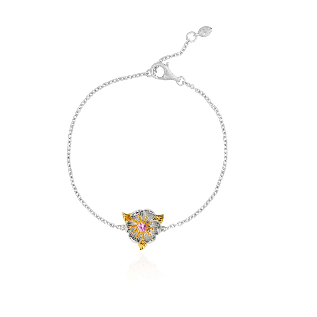 Risis Magnolia Blossom Bracelet - This is a delicate silver bracelet featuring a central flower-shaped charm with gold-tone petals and a pink gemstone at the core.