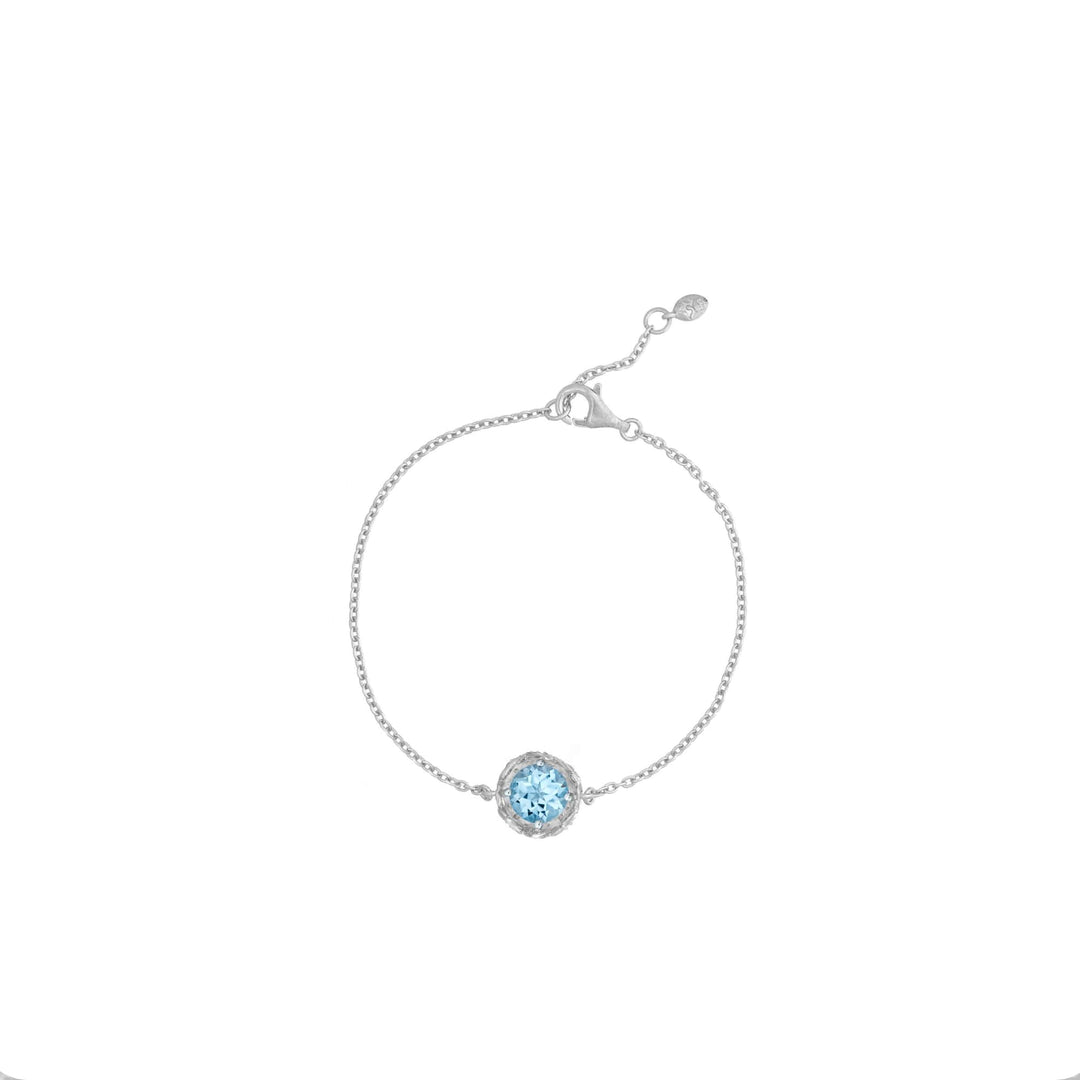 Risis Midori Bracelet With Sky Blue Topaz (RH) - A delicate silver bracelet with a thin chain and a central, sparkling light blue gemstone surrounded by a subtle ring of smaller clear crystals.