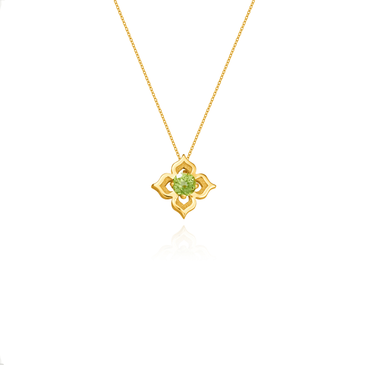 Risis Timeless Peranakan Small Necklace With Peridot - A golden pendant with a floral motif and a central green gem hangs on a delicate chain, displaying a blend of elegance and simplicity.