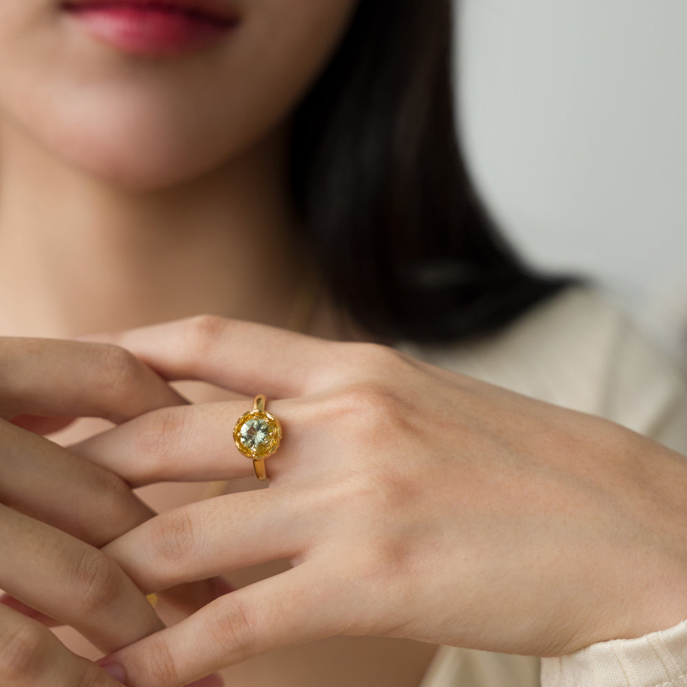 Risis Midori Ring with Prasiolite - A gold ring with a large, central yellow gemstone is displayed on a person's ring finger. The jewelry exudes elegance and simplicity.