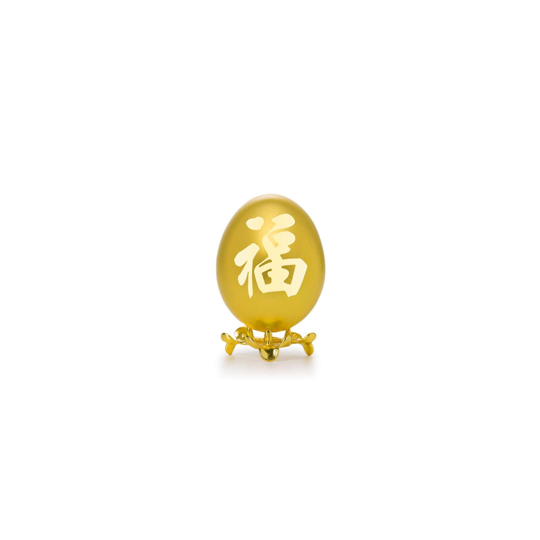 Risis Auspicious Egg - Fu (Small) - An oval, golden-yellow decorative object with a Chinese character engraved, displayed on a small, intricate gold stand.