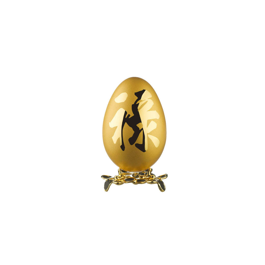 Risis Auspicious Egg - Lu (Medium) - A golden egg with intricate black silhouettes of figures and patterns rests on a gold stand with delicate, interwoven designs.