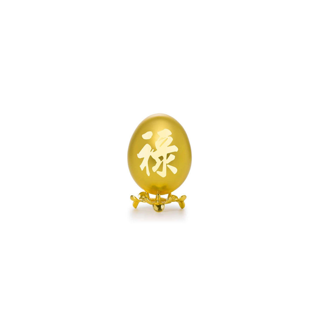 Risis Auspicious Egg - Lu (Small) - An oval, amber-colored object with Chinese character engravings stands on a delicate gold-toned support with curved legs.
