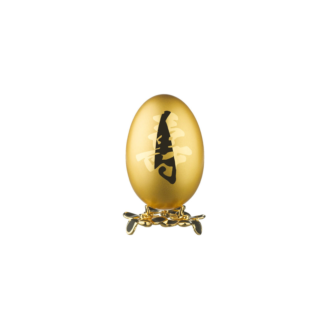 Risis Auspicious Egg - Shou (Medium) - A golden egg with a black script-like adornment stands on an elegant, ornate gold stand with delicate, petal-like features.