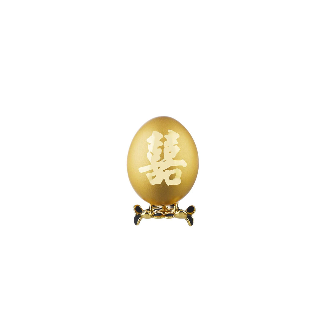 Risis Auspicious Egg - Xi (Small) - A golden egg with intricate Chinese characters etched on it, mounted on an ornate, bow-shaped stand.