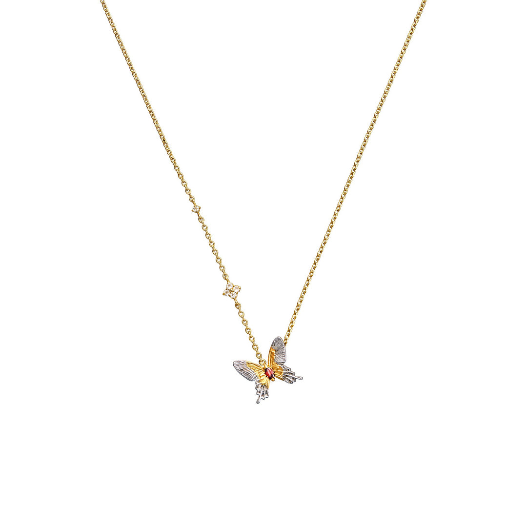 Risis Botanique Butterfly Necklace - A golden dragon sculpture rests on a wavy blue stand, with intricate detailing. Nearby, a metallic tree blooms from a small pot, and a ornate gold-splattered dish with a spoon completes the set.