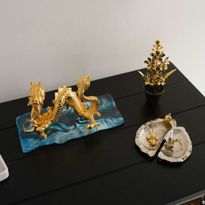 Risis Botanique Chestnut Bird Tray - A silver-colored, leaf-shaped decorative dish with a golden bird perched on the rim, exhibiting a contrast between the sleek silver finish and the bird's glossy gold.