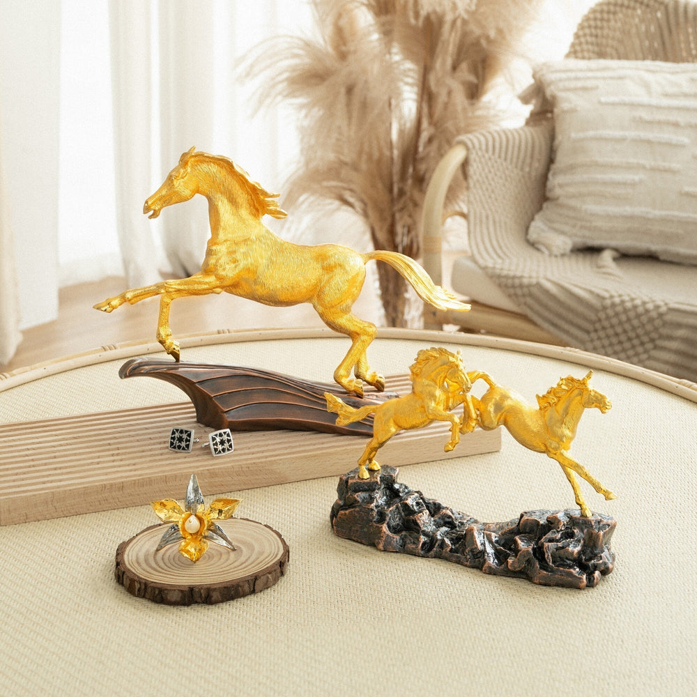 Risis Concord Horse - Golden figurines of horses in dynamic poses accompanied by an ornate, flower-shaped piece with a central gem on a wooden slice.