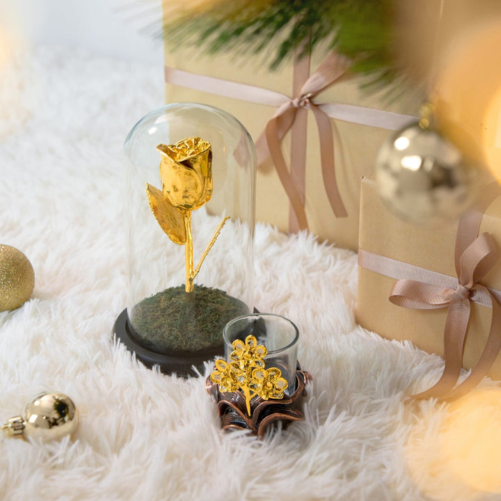 Risis Doritaenopsis Orchid Holder - A golden rose encased in a clear dome and a sparkling gold-colored flower inside a transparent cup rest on a soft white surface, emanating elegance and festive charm.