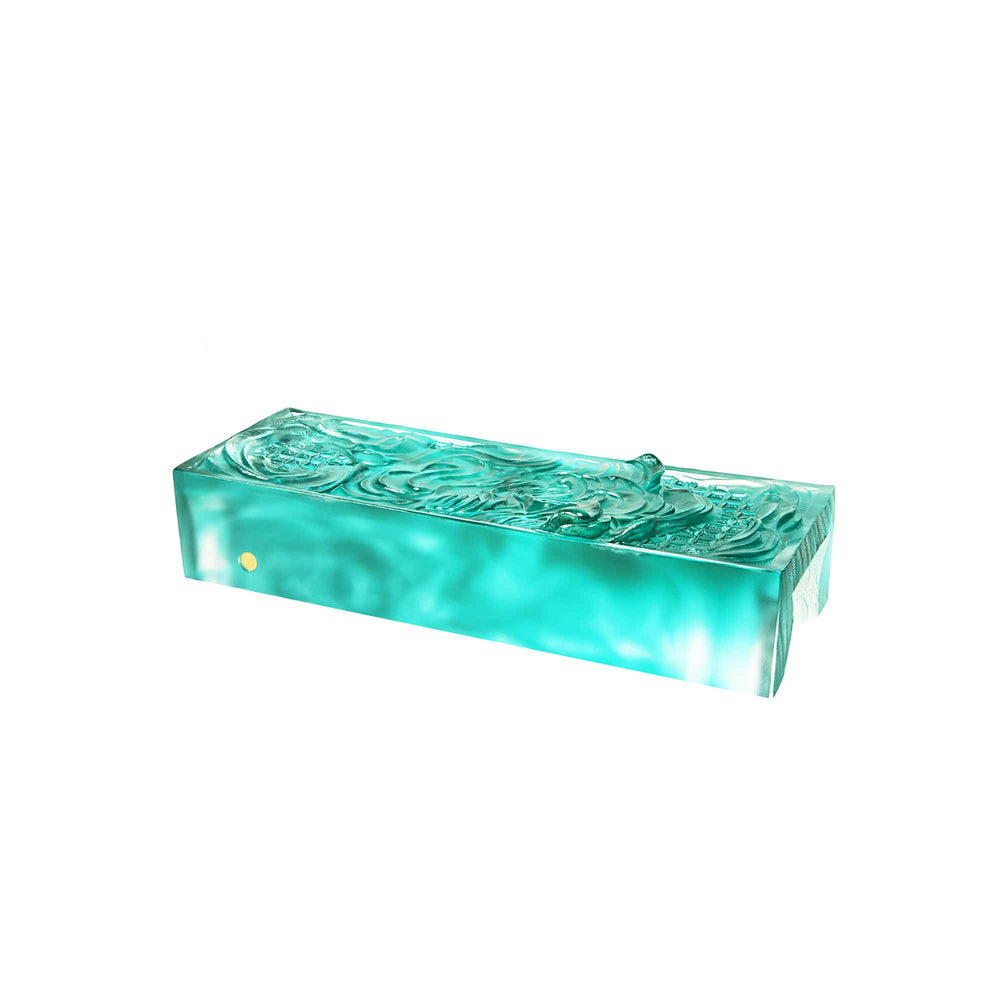 Risis Majestic Arowana - A rectangular, translucent turquoise object with intricate raised patterns, possibly made of glass or resin, exuding an artistic and decorative quality.