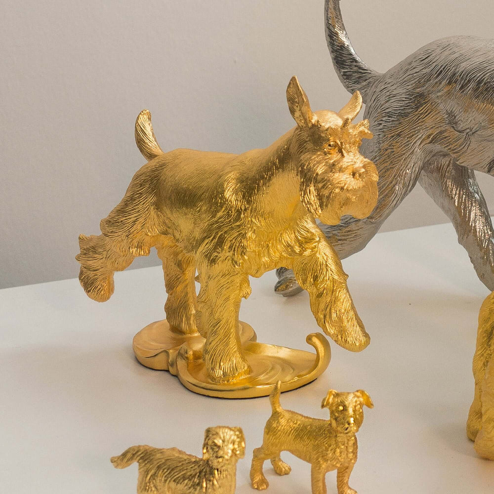 Risis Miracle Dog - A golden sculpture of a goat with textured fur is flanked by two smaller golden dogs, all depicted with a high level of detail.