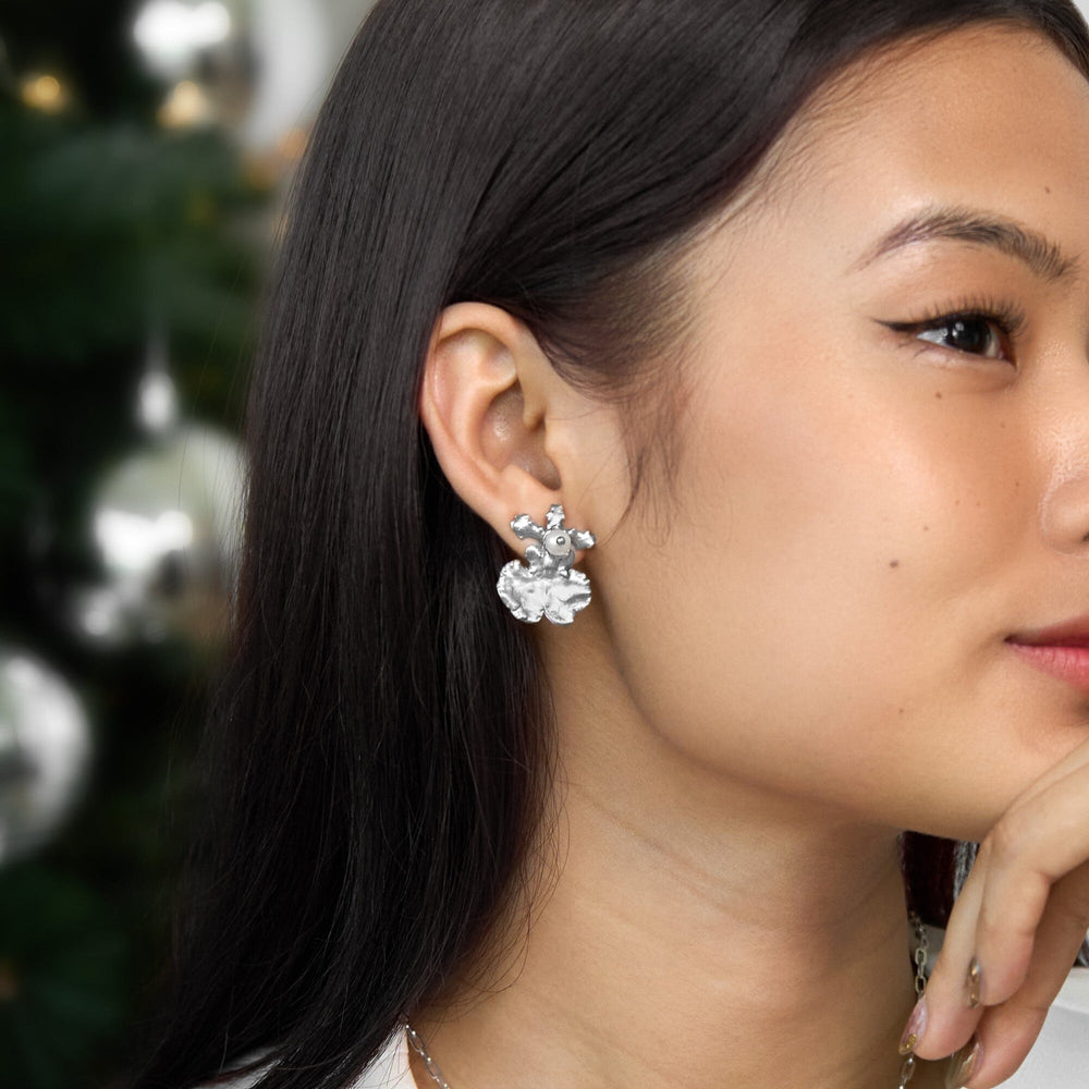 Risis Oncidium Shower Earrings (RH) - A person is wearing a silver, floral-design earring with intricate details and multiple petals, giving it an elegant appearance.
