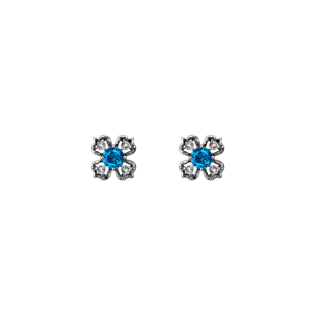 Risis Peranakan Kebaya Earrings (BRH) with London Blue Topaz - A pair of earrings, each shaped like a flower with a vibrant blue gemstone center, surrounded by silver petals patterned with smaller clear gemstones.