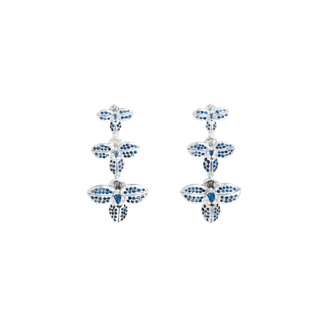Risis Rare Orchid Earrings with Blue Sapphire - A pair of silver earrings with blue and white gemstones, designed in a repeating floral pattern with three flowers vertically aligned.