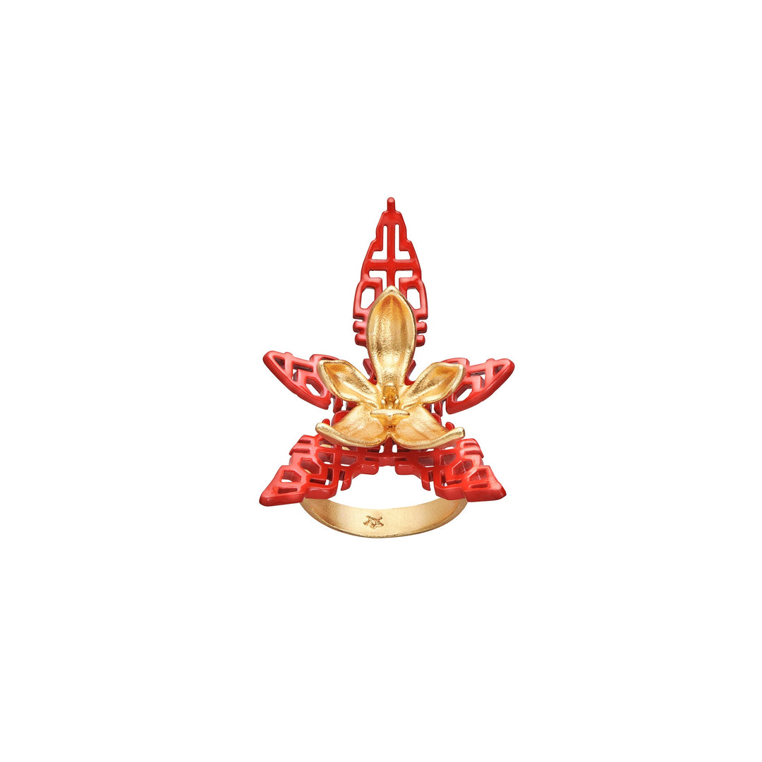 Risis X TRIOLOGIE Iconic Phalaenopsis Orchid Ring - A decorative object features a golden fleur-de-lis atop a red lattice structure with a circular base, presenting a contrast of ornate metallic detail against intricate cutouts.