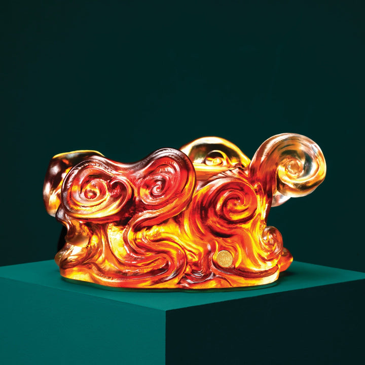 Risis The Imperial Dragon on Amber Liu Li - A vibrant glass sculpture with swirling patterns of red, orange, and yellow sits atop a pedestal, resembling flames with its glossy, fluid shapes.