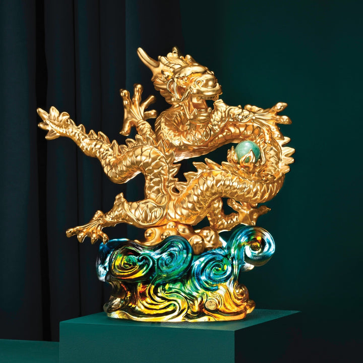 Risis The Imperial Dragon on Blue Liu Li - A golden dragon sculpture with intricate scales clutches a pearl, rising from swirling, iridescent blue and green clouds, symbolizing power and grace.