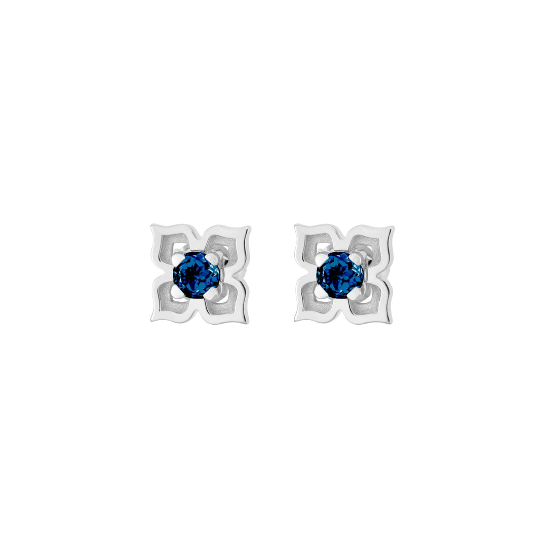 Risis Timeless Peranakan II Earrings (RH) with London Blue Topaz - A pair of earrings with silver, four-petaled flower-shaped settings, each centering a striking, round-cut blue gemstone.