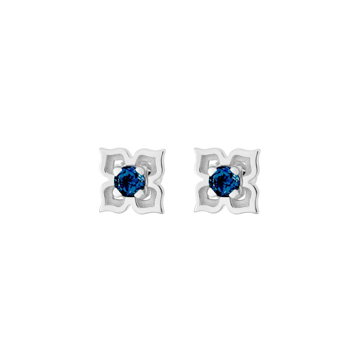 Risis Timeless Peranakan II Earrings (RH) with London Blue Topaz - A pair of earrings with silver, four-petaled flower-shaped settings, each centering a striking, round-cut blue gemstone.