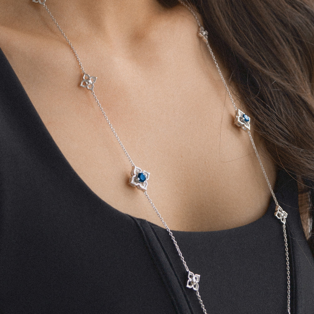 Risis Timeless Peranakan II Necklace (RH) with London Blue Topaz - A silver necklace with star-shaped pendants and a central blue gemstone adorns a person's neck, exuding elegance and simplicity.