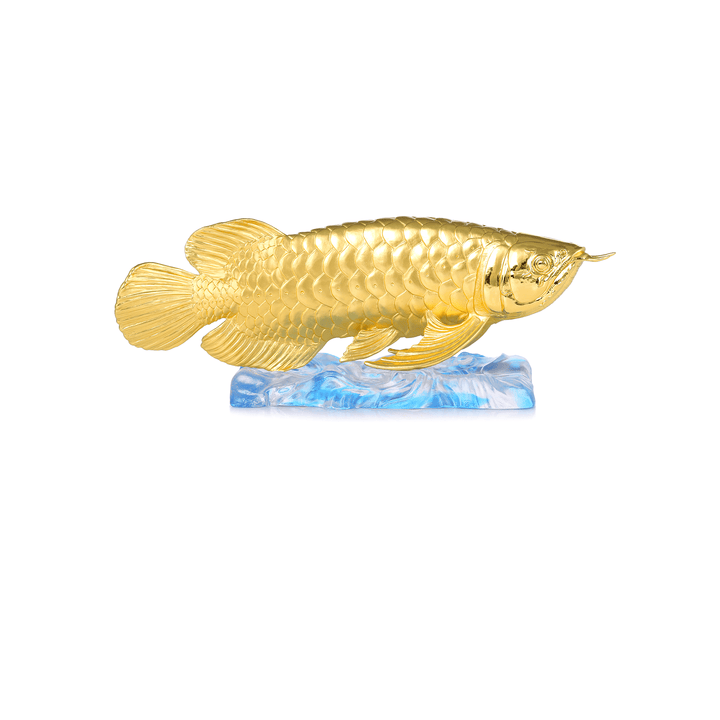 Risis Treasure Arowana - A golden fish sculpture with detailed scales and fins is perched atop a translucent blue wave-like base, creating an impression of motion and elegance.
