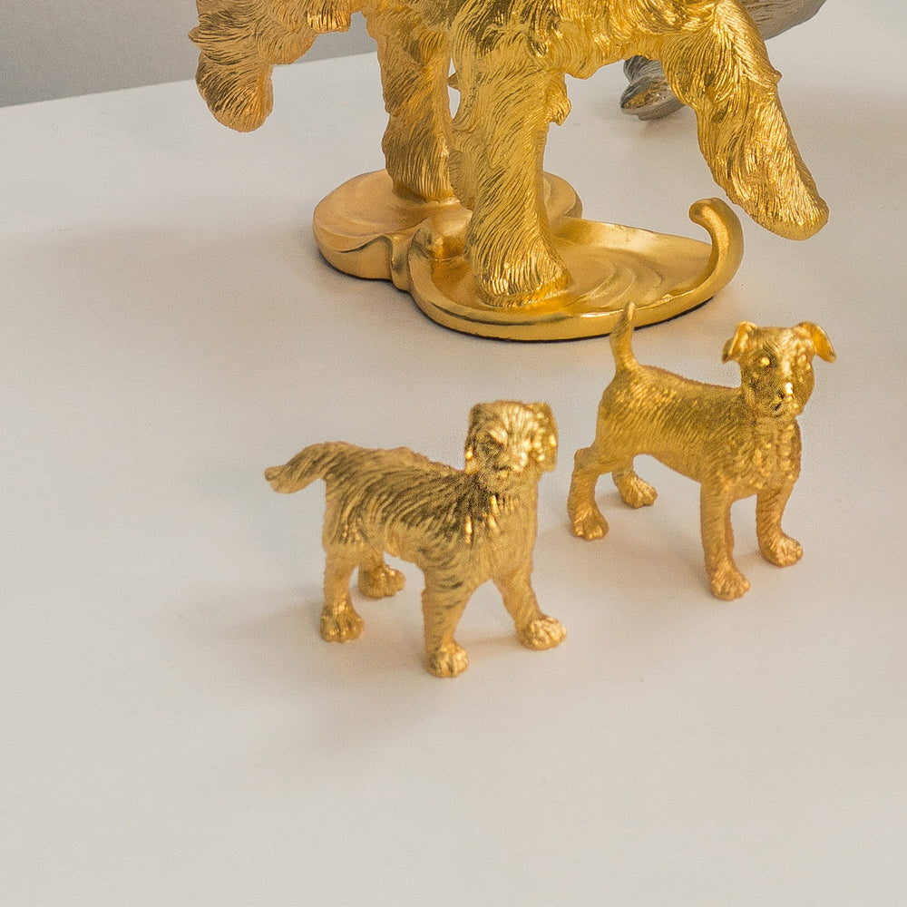 Risis Zodiac Dog Figurine - Two small golden dog figurines with textured surfaces stand on a flat surface, resembling lifelike poses and detailed features.