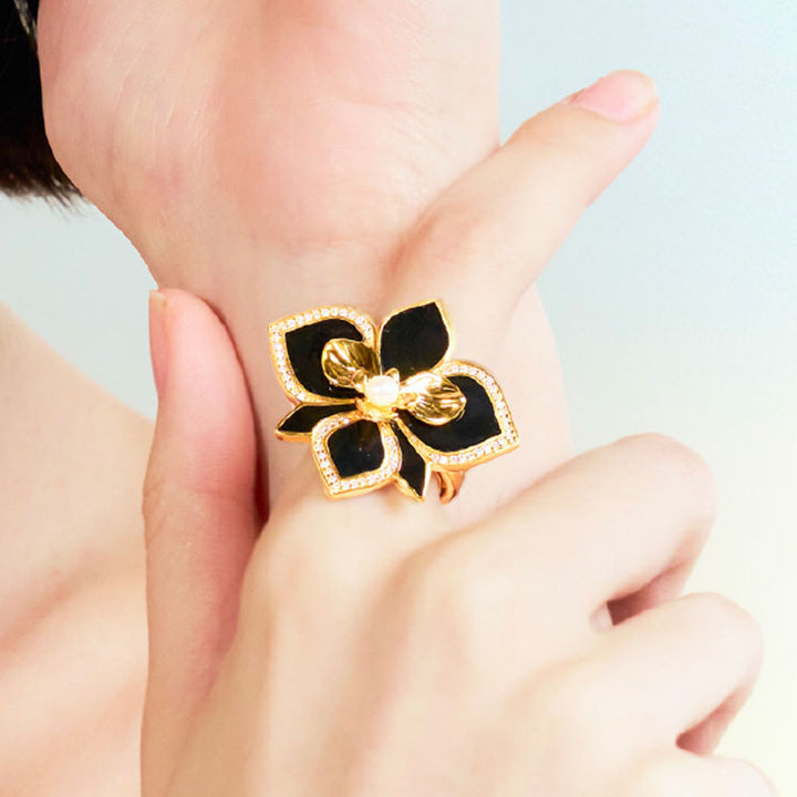 Orchid ring with black enamel petals, pavé-set edges, and central pearl