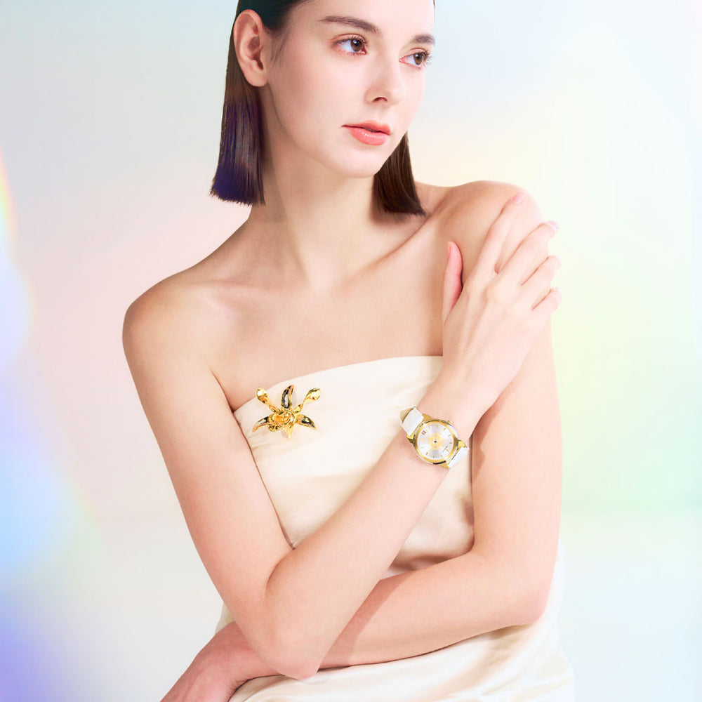 Women’s wristwatch on wrist with white dial, gold-tone case, and white leather strap