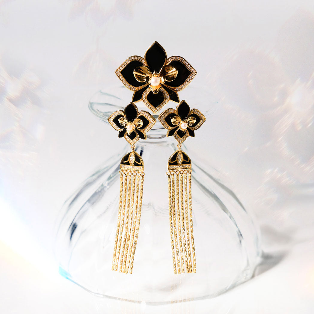 Orchid earrings with black enamel flowers, pavé details, and gold tassels