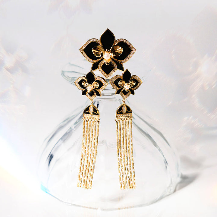 Orchid earrings with black enamel flowers, pavé details, and gold tassels