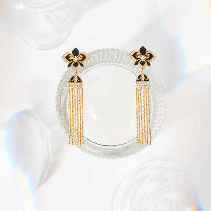 Orchid drop earrings with black floral motif and long gold tassels