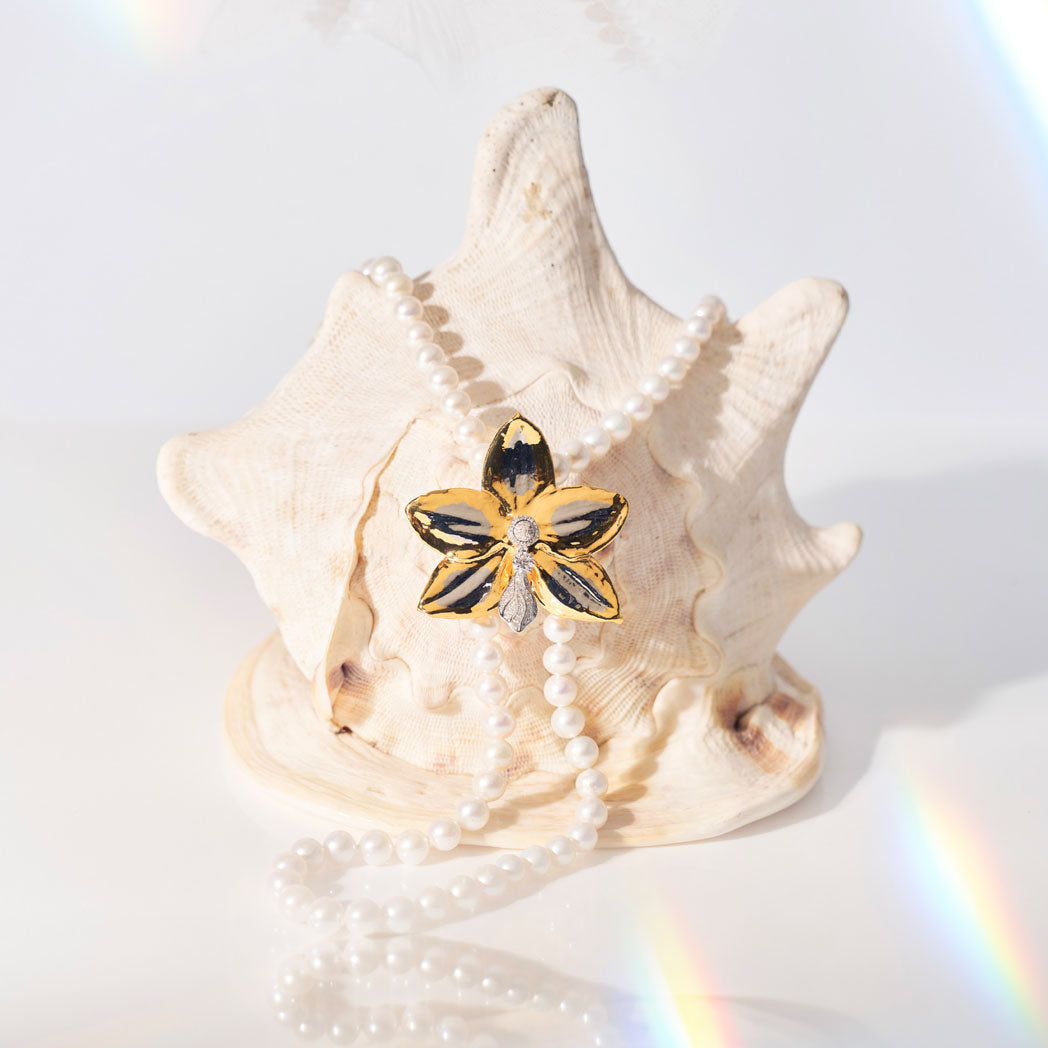 Gold-tone orchid flower brooch with faux pearls and a small dark center
