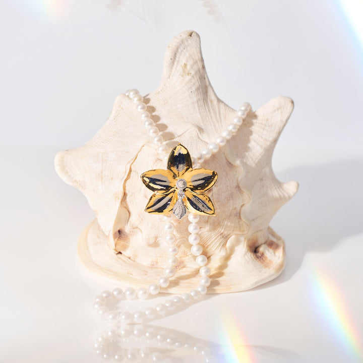 Gold-tone orchid flower brooch with faux pearls and a small dark center