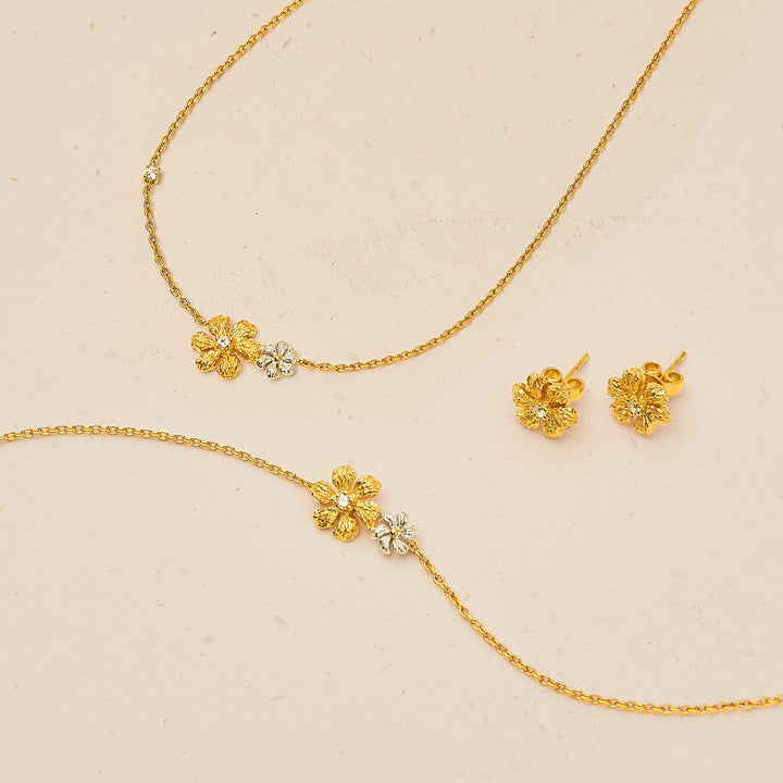 Risis Enchanted Jasmine Bracelet II - Golden jewelry with floral motifs and embedded crystals arranged neatly includes two dainty chains and a pair of matching earrings, exuding elegance and craftsmanship.