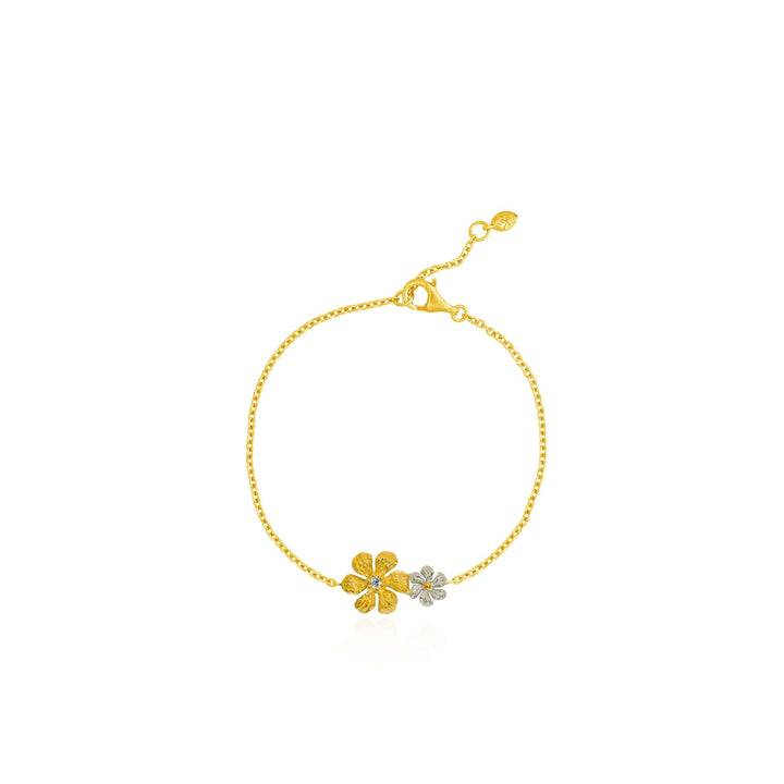 Risis Enchanted Jasmine Bracelet II - A golden bracelet features a delicate chain with two small, contrasting flowers, one shimmering silver and the other textured gold.