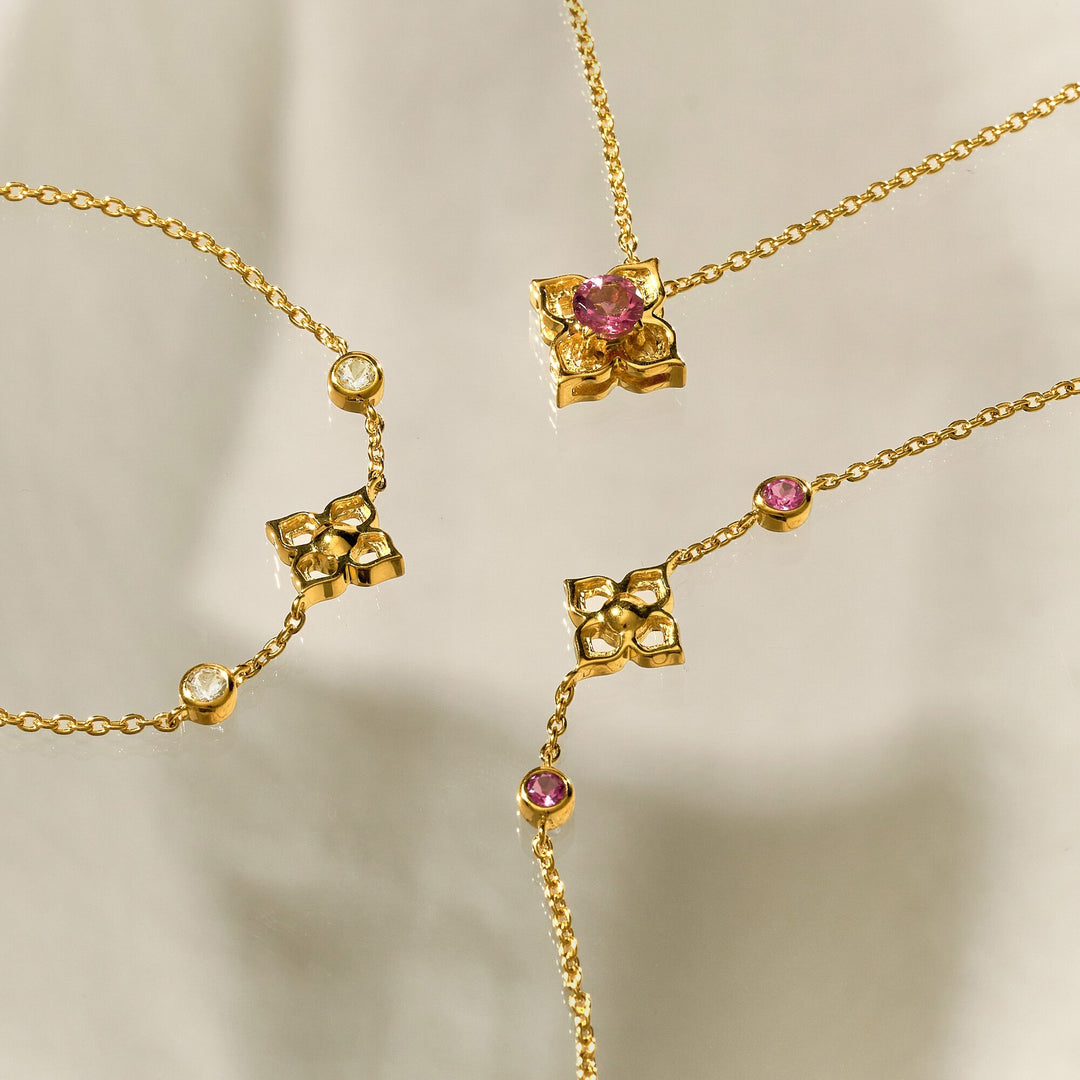 Risis Timeless Peranakan Bracelet With Pink Tourmaline - Gold chain jewelry with interspersed pink gemstones and ornamental gold flowers. The design is delicate and elegant.