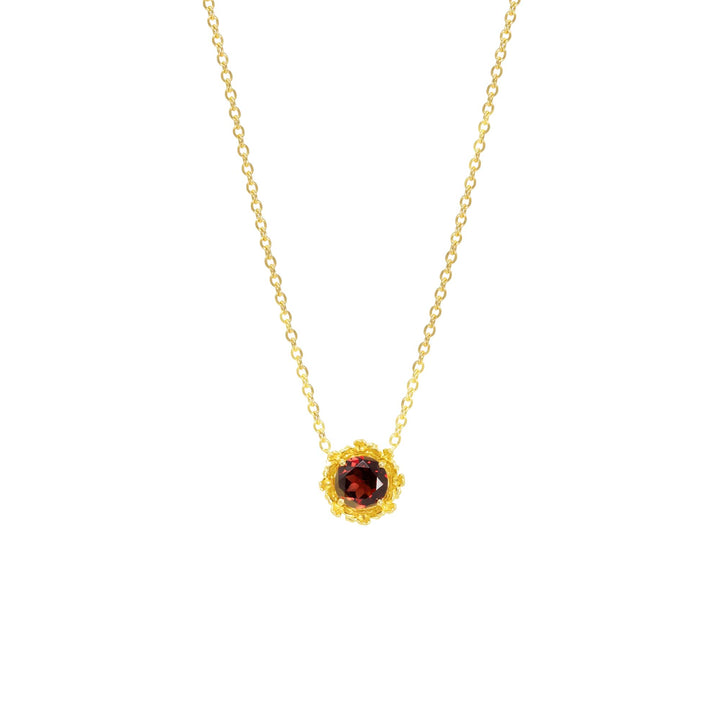 Risis Majestic Vanda Necklace With Red Garnet - A gold necklace with a delicate chain holds a central, round garnet gem encased in an intricate golden floral bezel setting, radiating luxury and elegance.