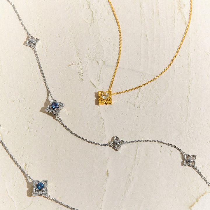 Risis Timeless Peranakan Ii Necklace Rh With London Blue Topaz - Three necklaces with star-shaped pendants and central blue stones; one has a gold chain, while the others have silver chains.