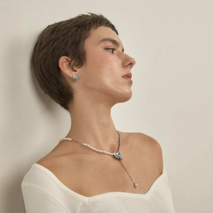 Risis Phalaenopsis Moments Earring - A person is wearing elegant pearl earrings and a matching necklace with silver and pearl accents, exuding a sense of classic sophistication.