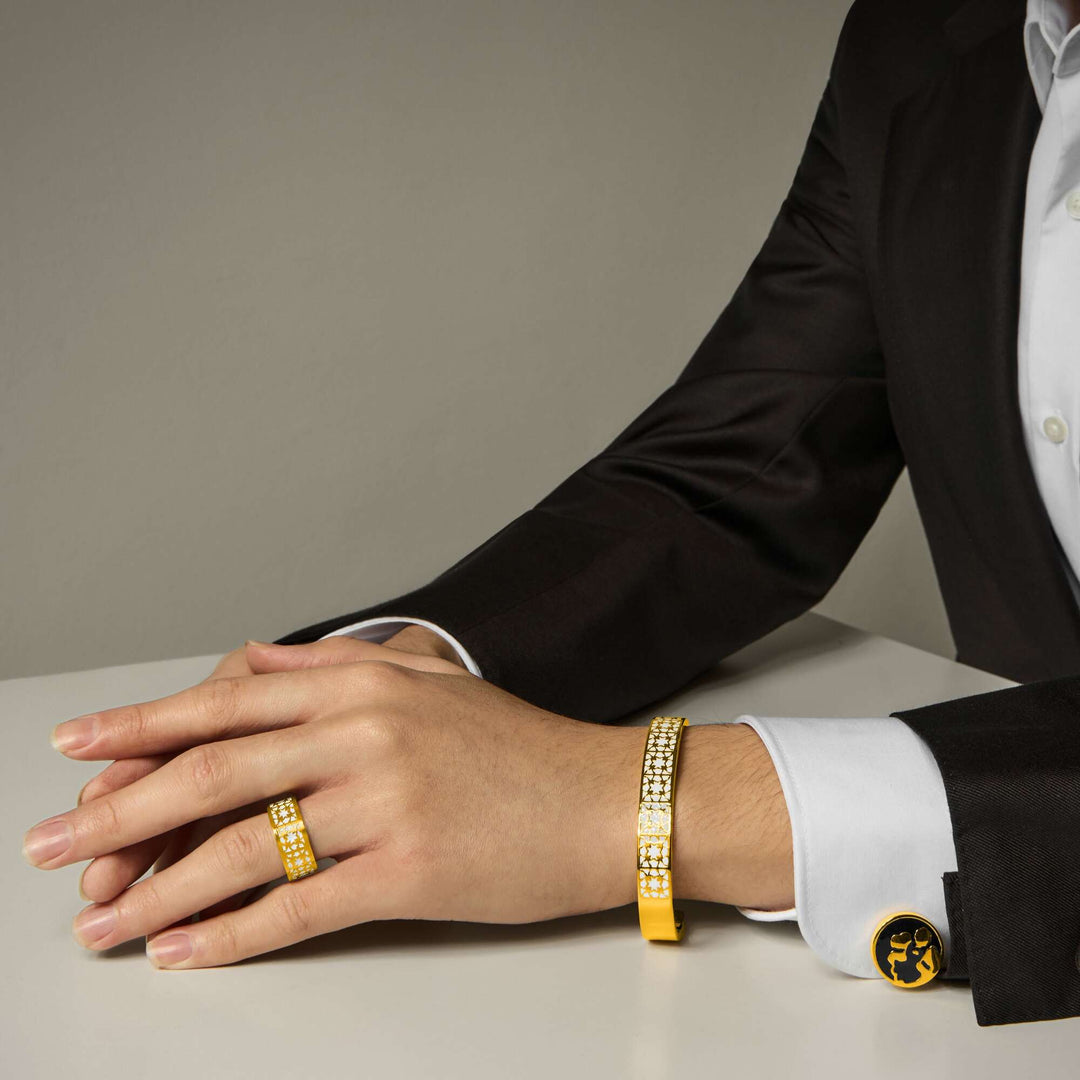 Risis Vanda Miss Joaquim Cufflinks G - A person's wrist adorned with a sparkling gold bracelet and ring, the jewelry embellished with numerous small gleaming stones, alongside a cufflink with a circular emblem.