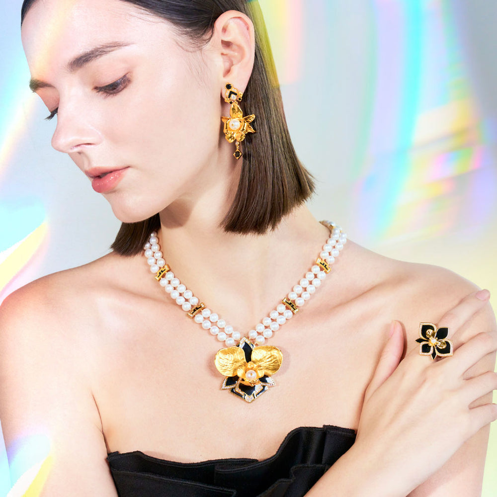 White pearl necklace with gold flower pendant worn at the collar