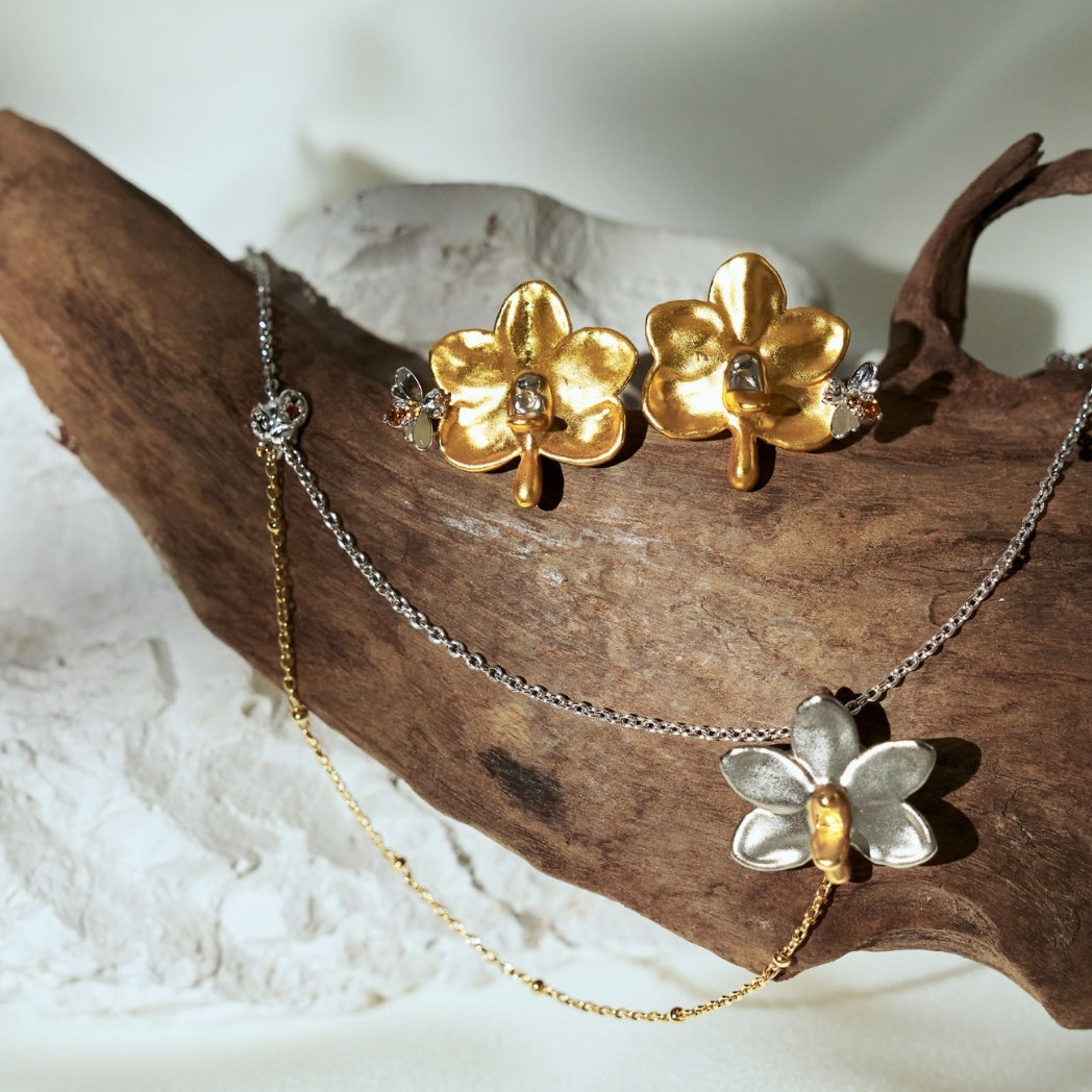 RISIS jewelry set featuring the Ladybird’s Orchid Trail Necklace and matching Bee-on earrings, crafted from natural orchids encapsulated in 24K gold and palladium with citrine accents.