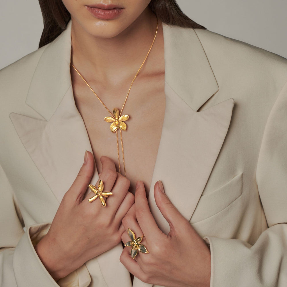 RISIS Orchid Long Slider Necklace (Natural Aeridovanda Vieng Ping orchid and brass chain encapsulated in 24K Swiss Gold), Orchid Rings (Natural Renanthanda Sawadi Orchid encapsulated in 24K Swiss Gold, Natural Phalaenopsis Orchid Encapsulated in 24K Swiss Gold and Palladium)