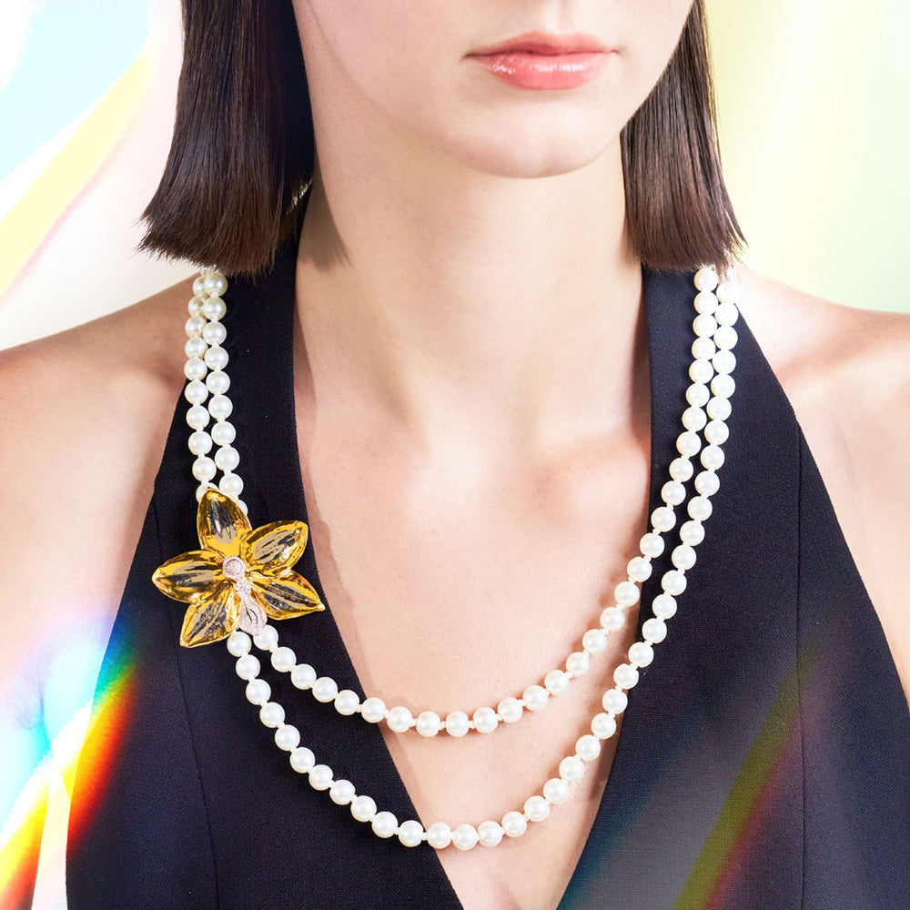 Gold orchid pearl brooch with diamond-like accents, on layered pearl strands