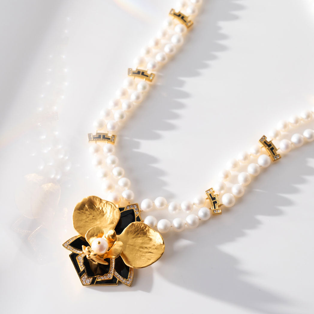 Close-up of white pearl necklace with gold links and gold flower pendant