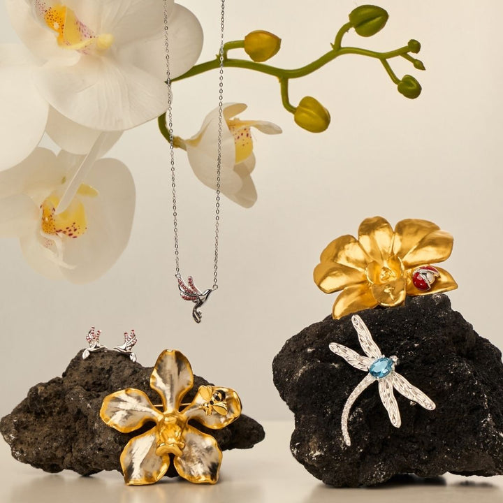 RISIS Sunbird Whispers Necklace and Earrings - 925 sterling silver in Rhodium with Red Garnets; RISIS Natural Vanda Orchid Bee-on-Brooch encapsulated in 24K Swiss Gold and Palladium; RISIS Sunbird Whispers Necklace and Earrings - 925 sterling silver in Rhodium with Red Garnets; RISIS Natural Vanda Orchid Bee-on-Brooch encapsulated in 24K Swiss Gold and Palladium
