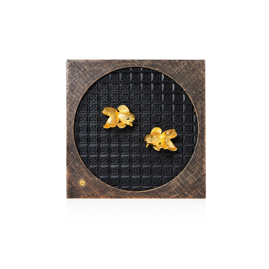 Risis Circle of Harmony Goldfish Frame - A square decorative object with a textured border encloses a central round, black area patterned with small squares. Two golden fish figures adorn the central part.