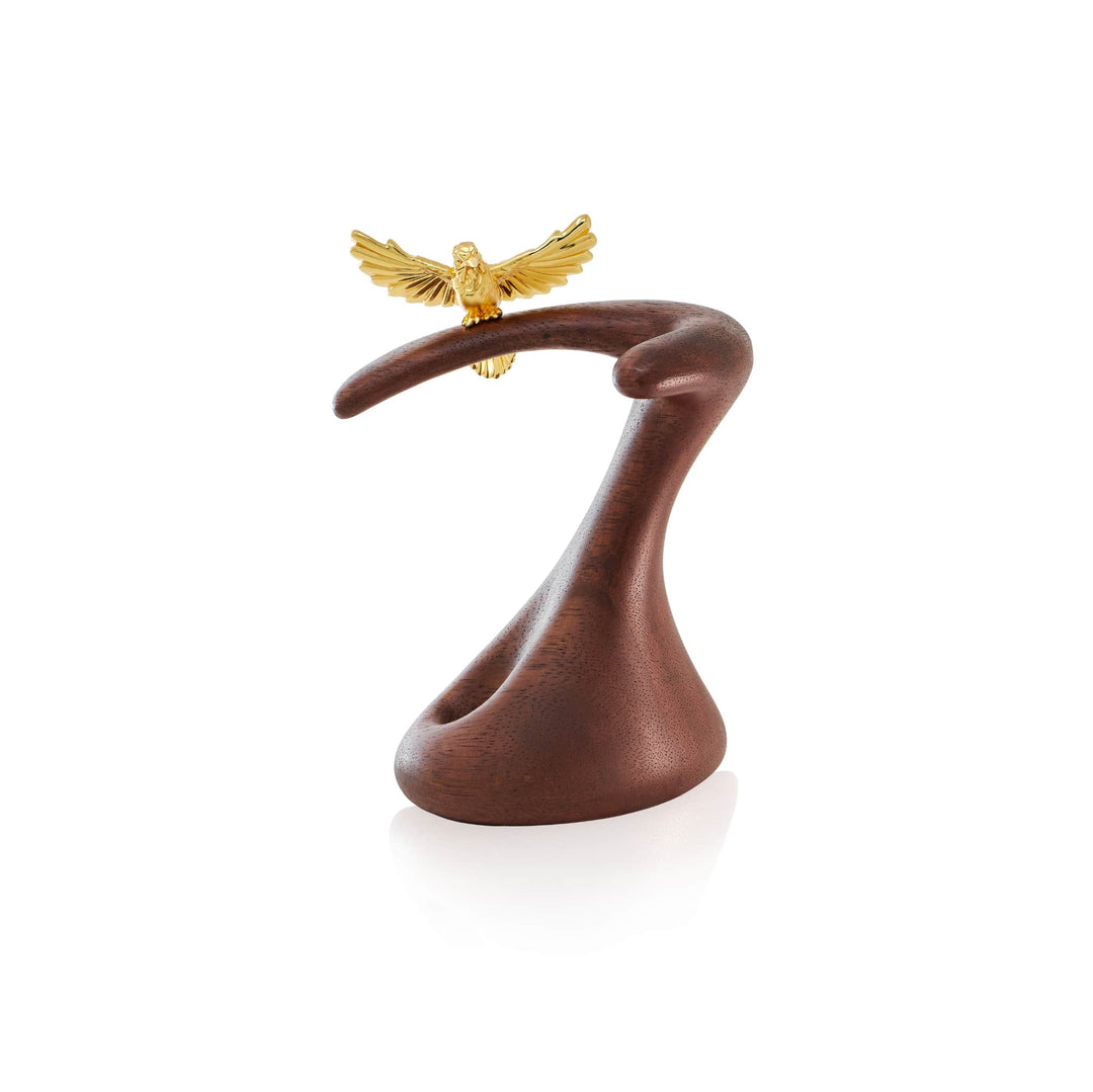 Risis Crimson Sunbird Pen Holder - A sleek, dark brown abstract sculpture with a graceful curved shape, topped by a small, detailed gold eagle with outstretched wings, creating an impression of elegance and motion.